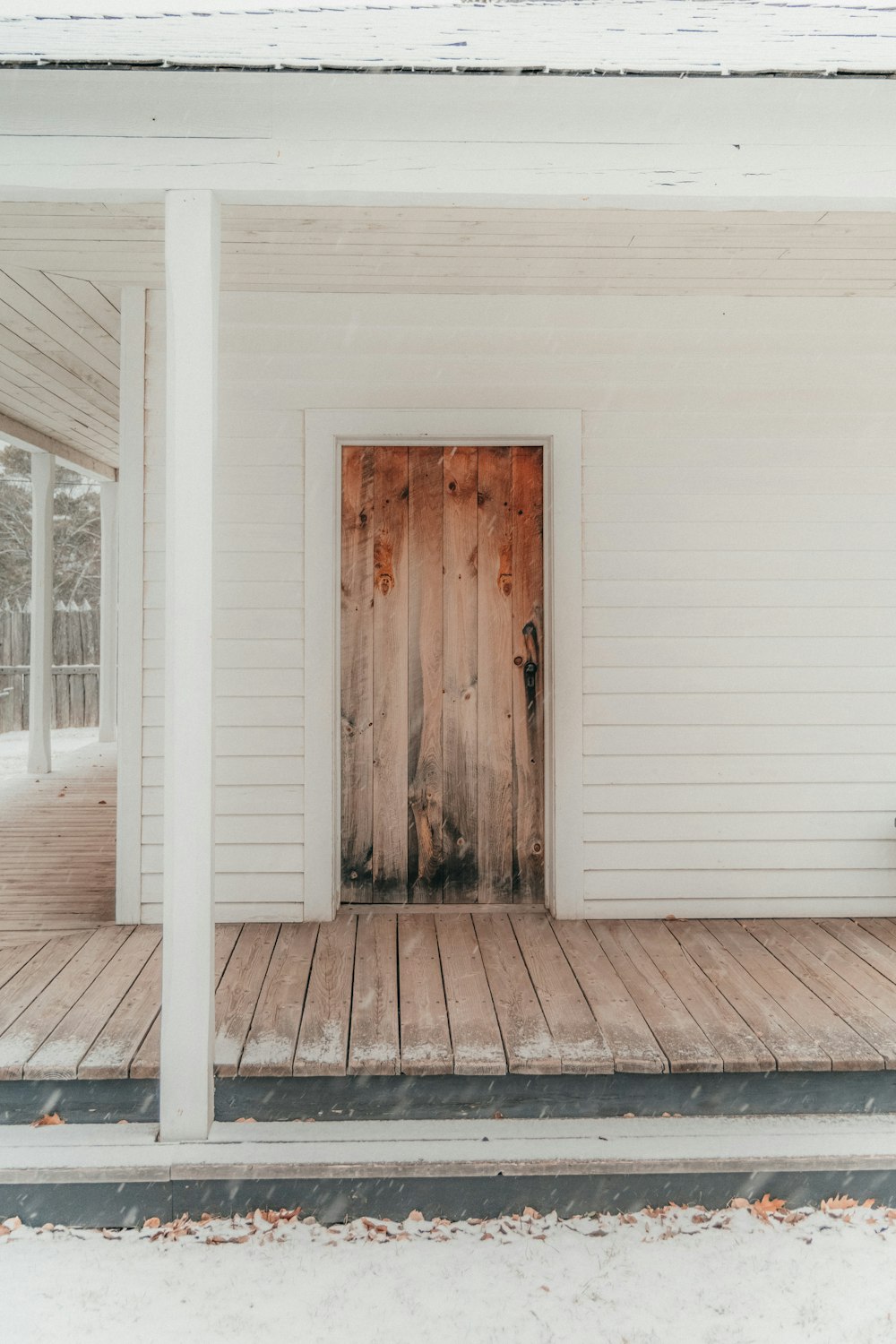 Ein weißes Haus mit Holztür und Veranda