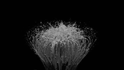 Close-up of a colorful explosion of paint splashes frozen mid-air against a white background.