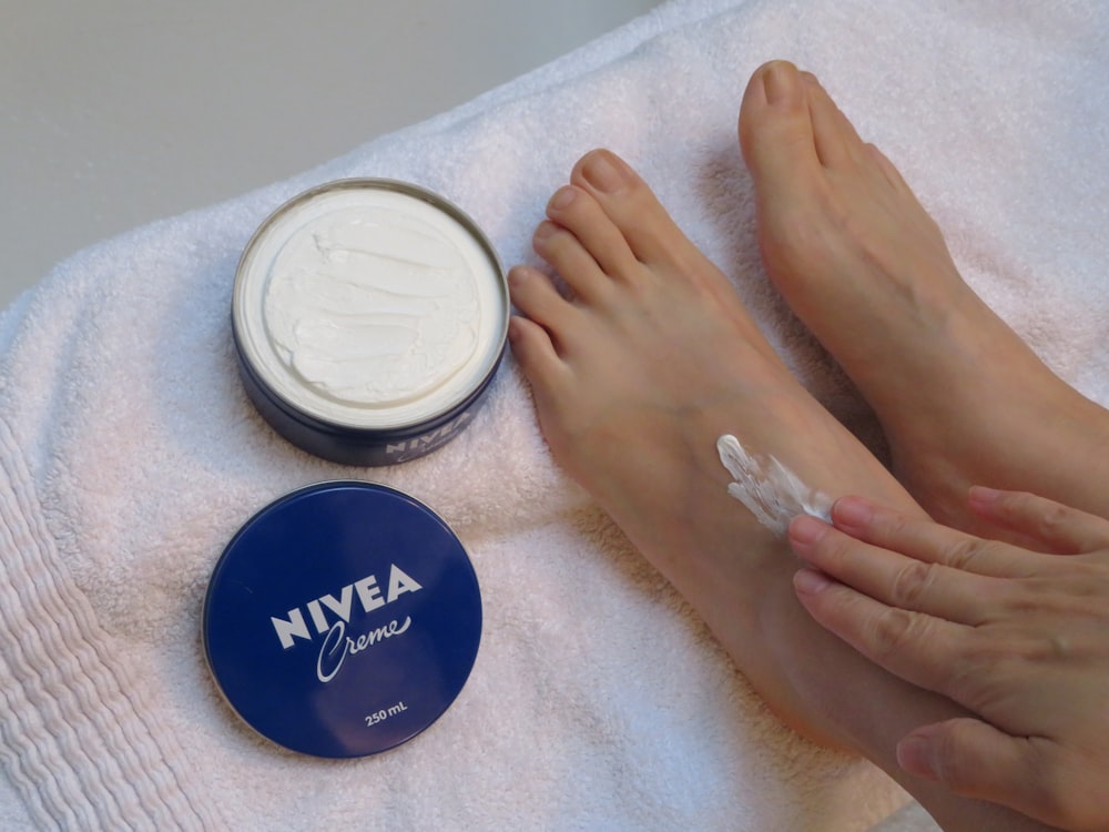 a person laying on a towel next to a jar of cream