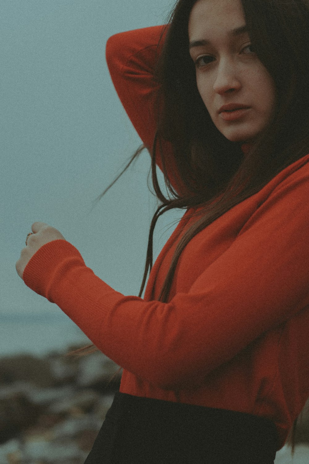 a woman in a red hoodie standing by the ocean