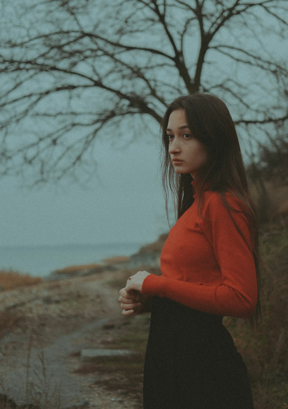 Une femme debout devant un arbre avec un plan d’eau en arrière-plan