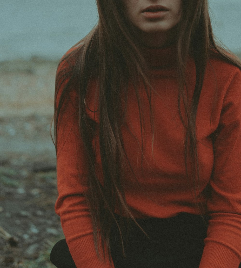 a woman with long hair sitting on the ground