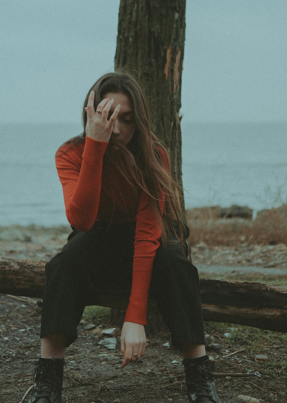 a woman sitting on a log next to a tree