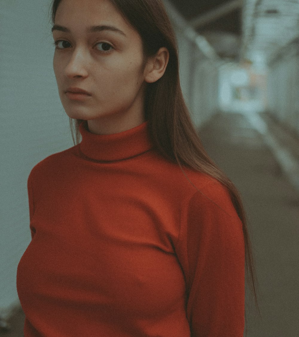 a woman in a red shirt standing in a hallway