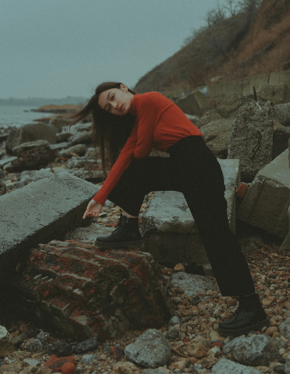 a woman in a red shirt leaning on a rock