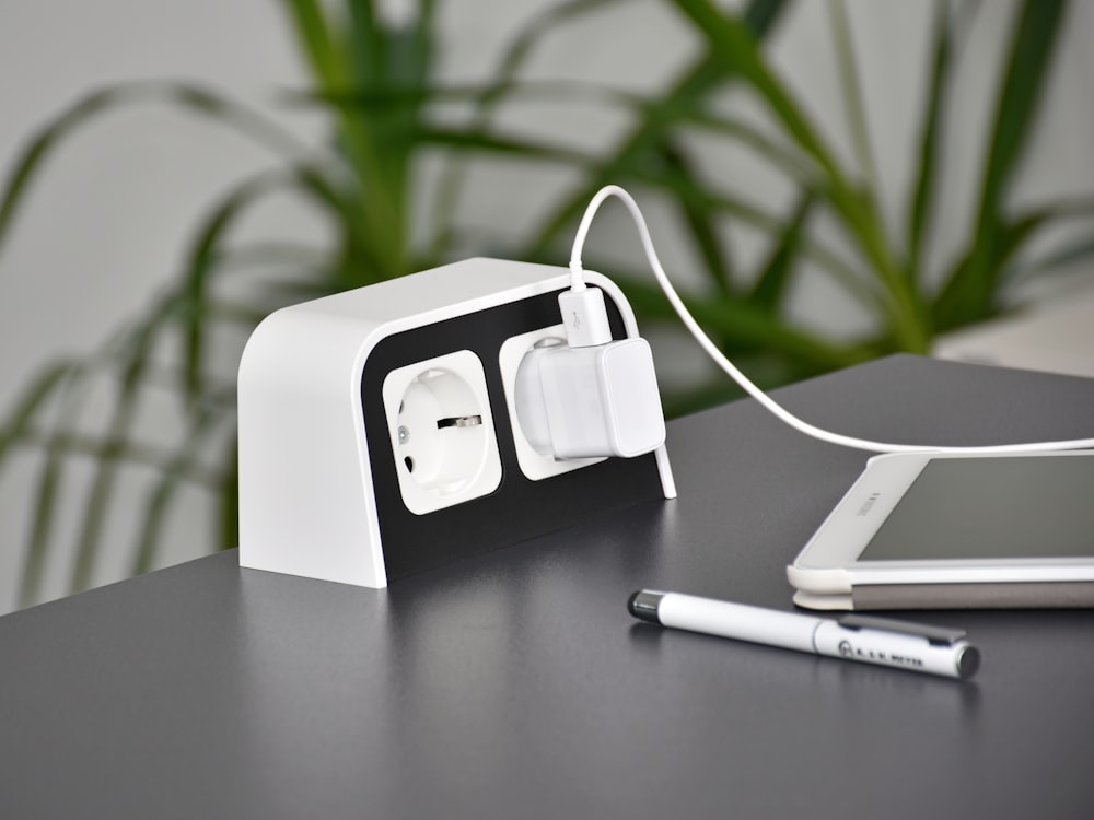 an electronic device charging on a table next to a cell phone