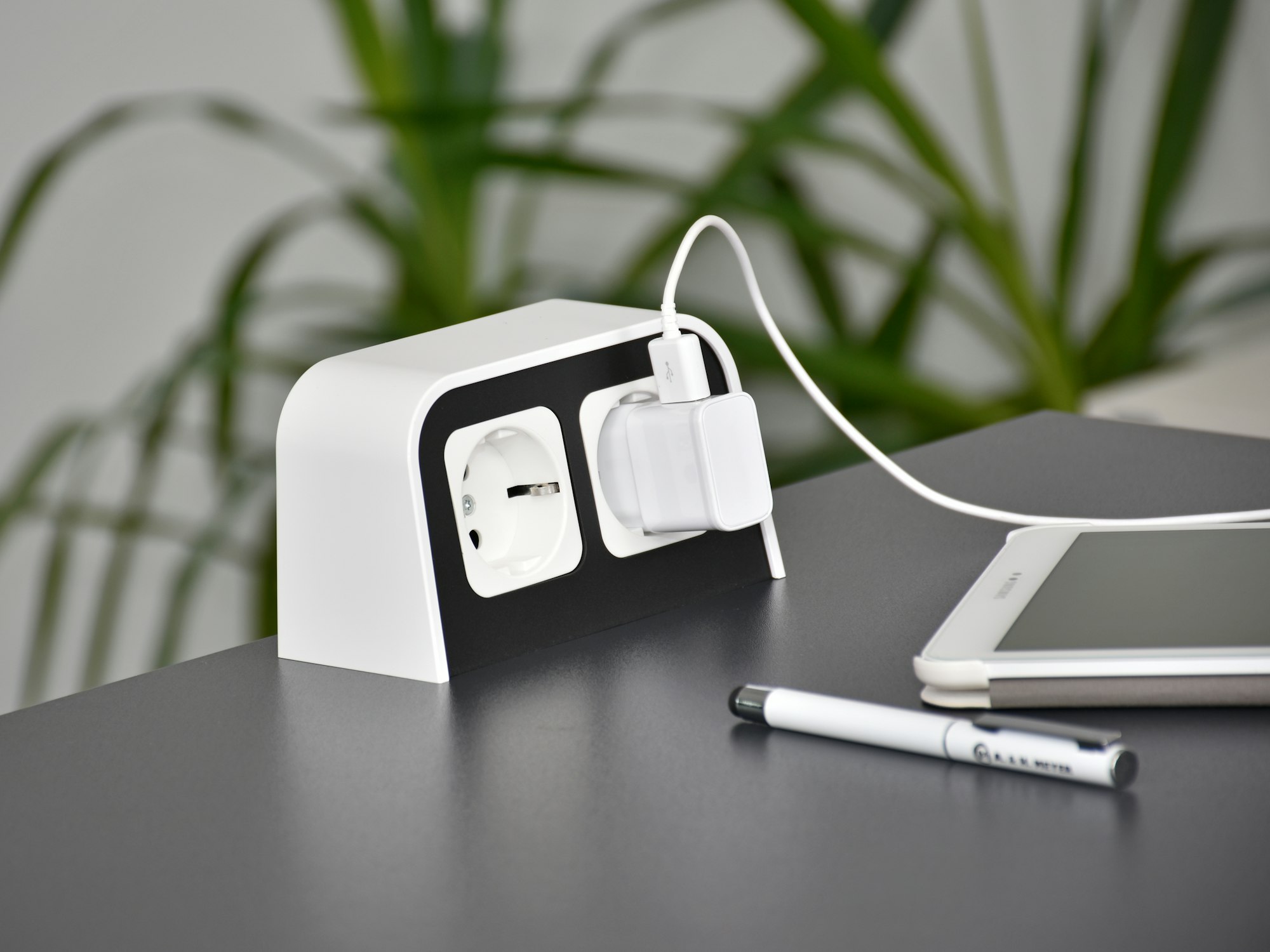Desktop socket white with tablet and green plant