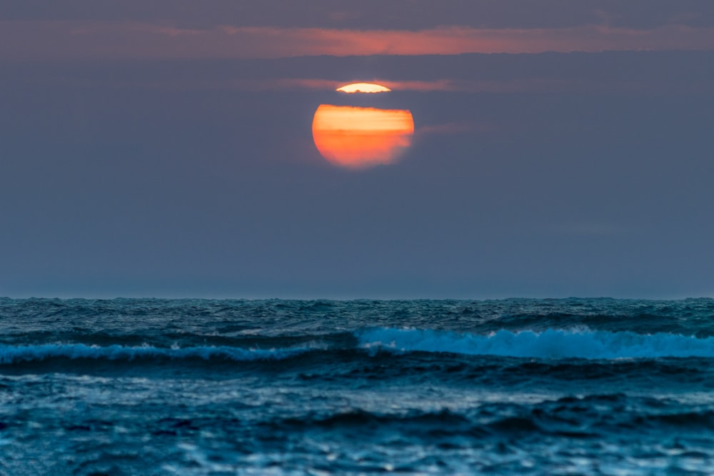 the sun is setting over the ocean waves