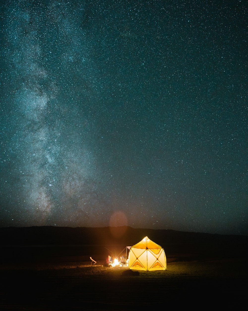 a tent in the middle of a field with the milky in the background