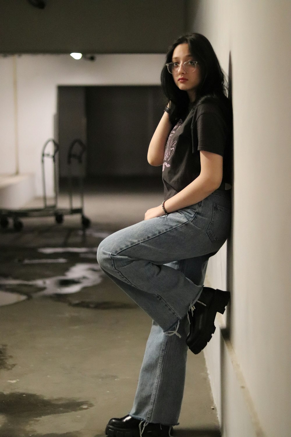 a woman leaning against a wall while talking on a cell phone