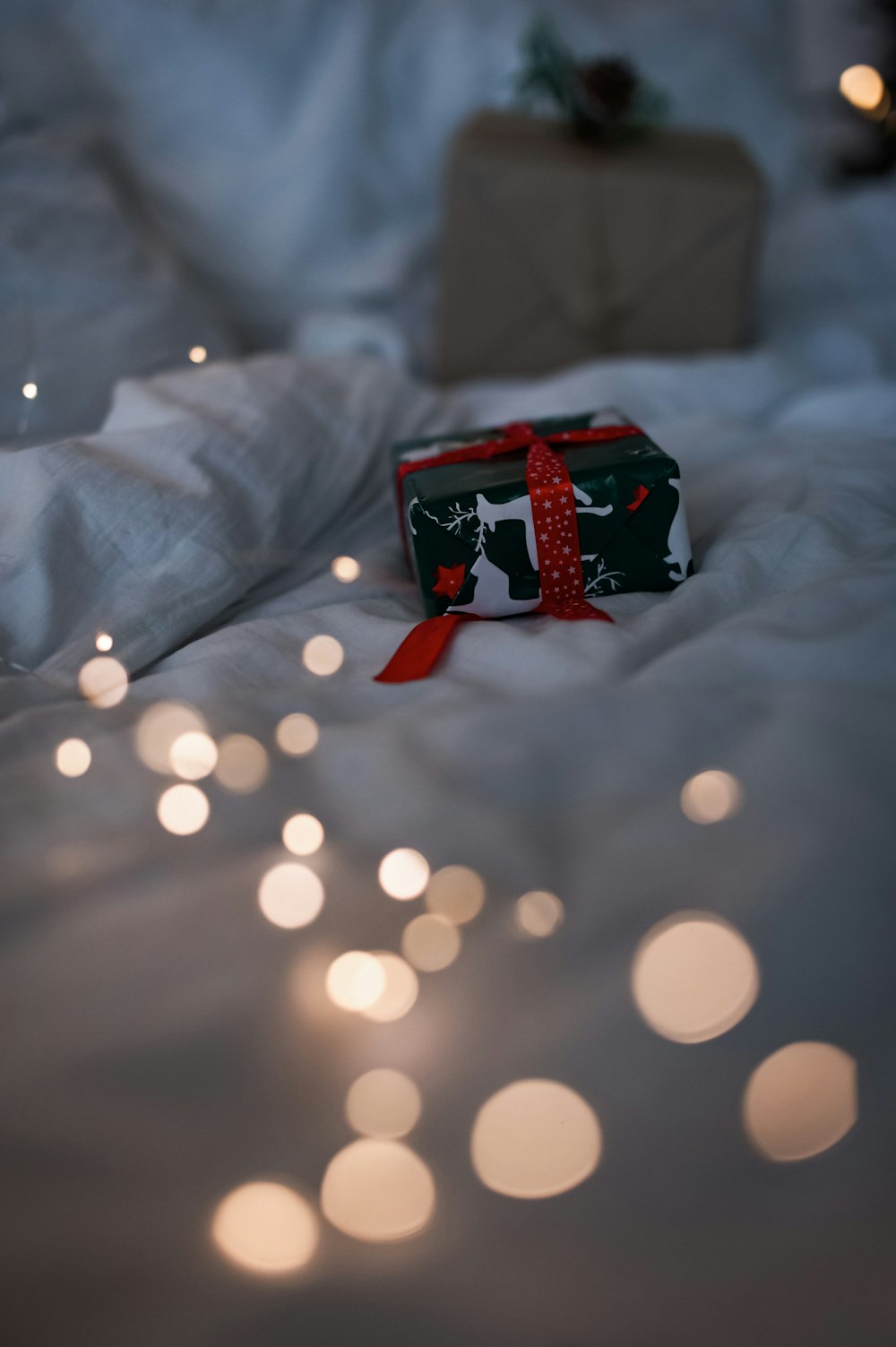 a present wrapped in a red ribbon on a bed