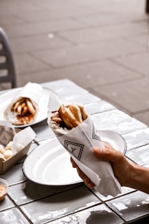 a person holding a napkin around gyros over a plate of food