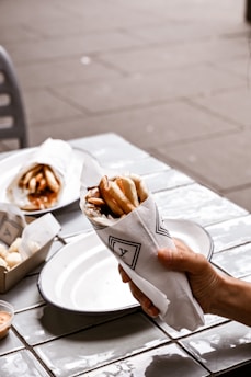 a person holding a napkin around gyros over a plate of food