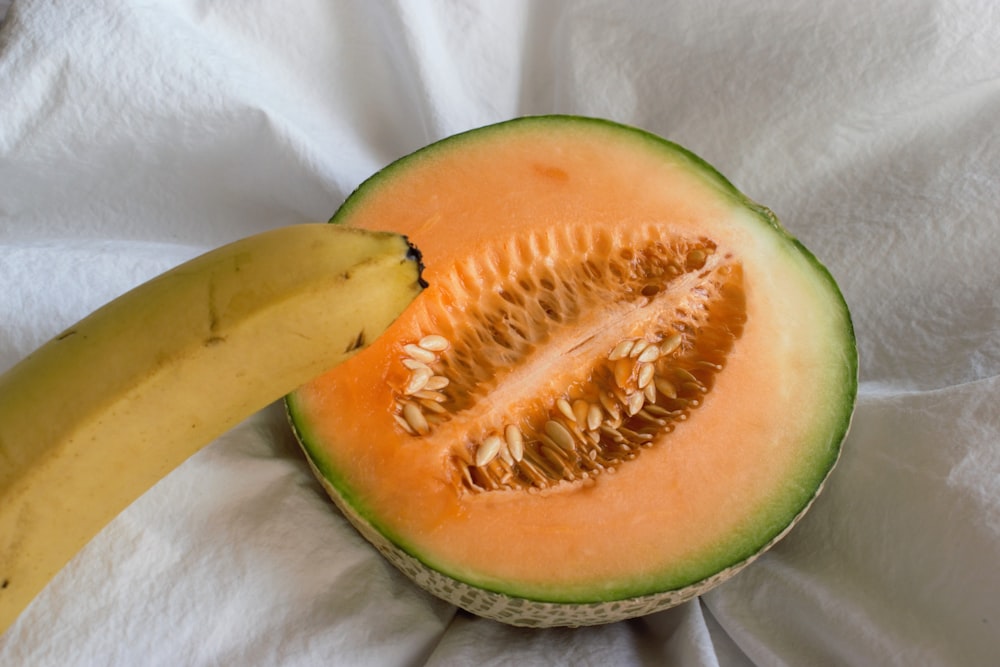 la mitad de una sandía y un plátano sobre un paño blanco