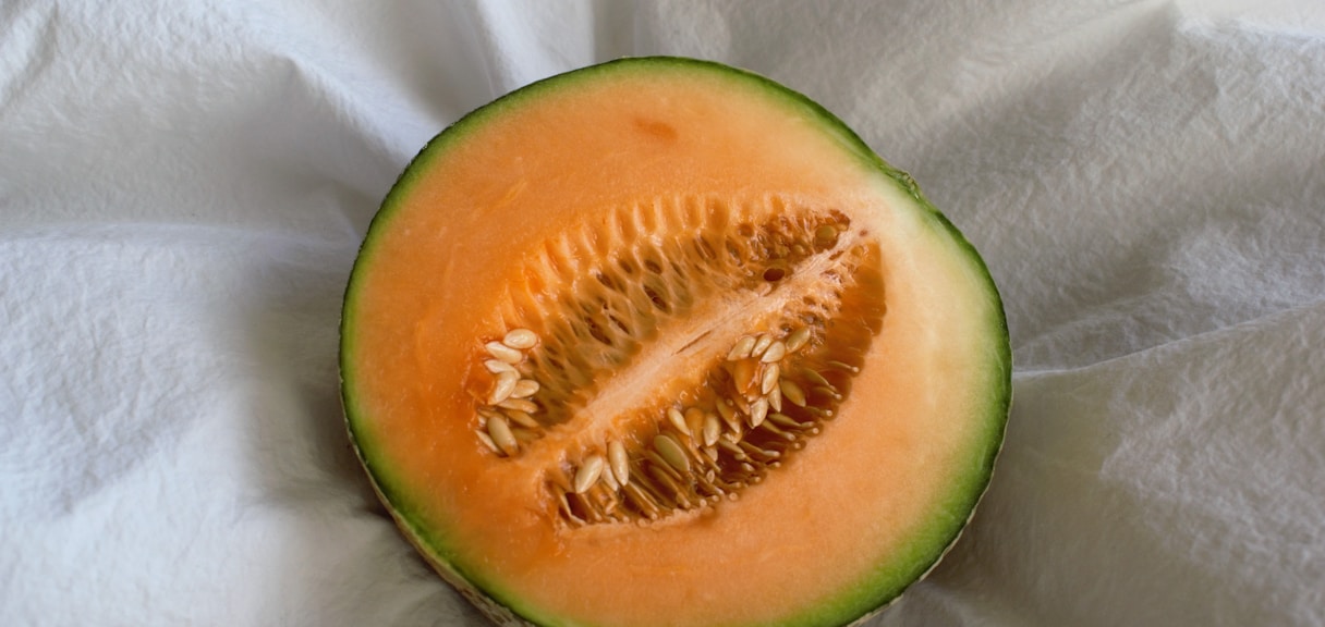 a cut in half melon sitting on top of a white cloth