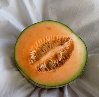 a cut in half melon sitting on top of a white cloth
