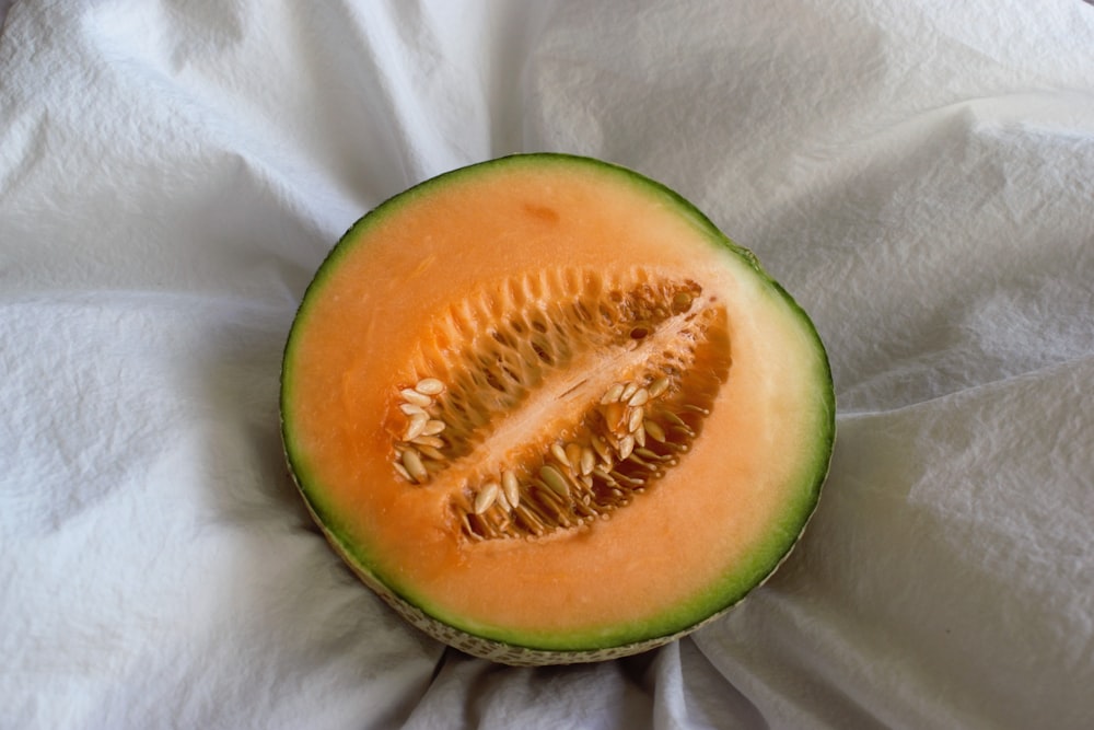 a cut in half melon sitting on top of a white cloth