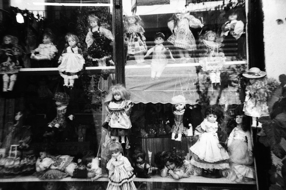 a black and white photo of dolls in a window