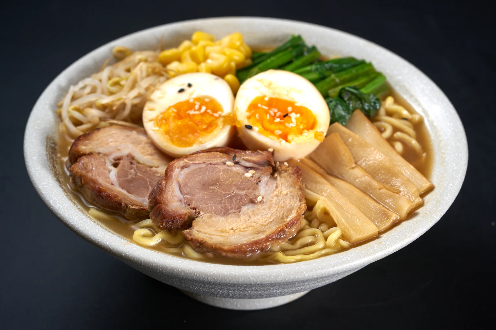 Ciotola di ramen con brodo caldo, fette di maiale, uovo marinato, germogli di soia e verdure