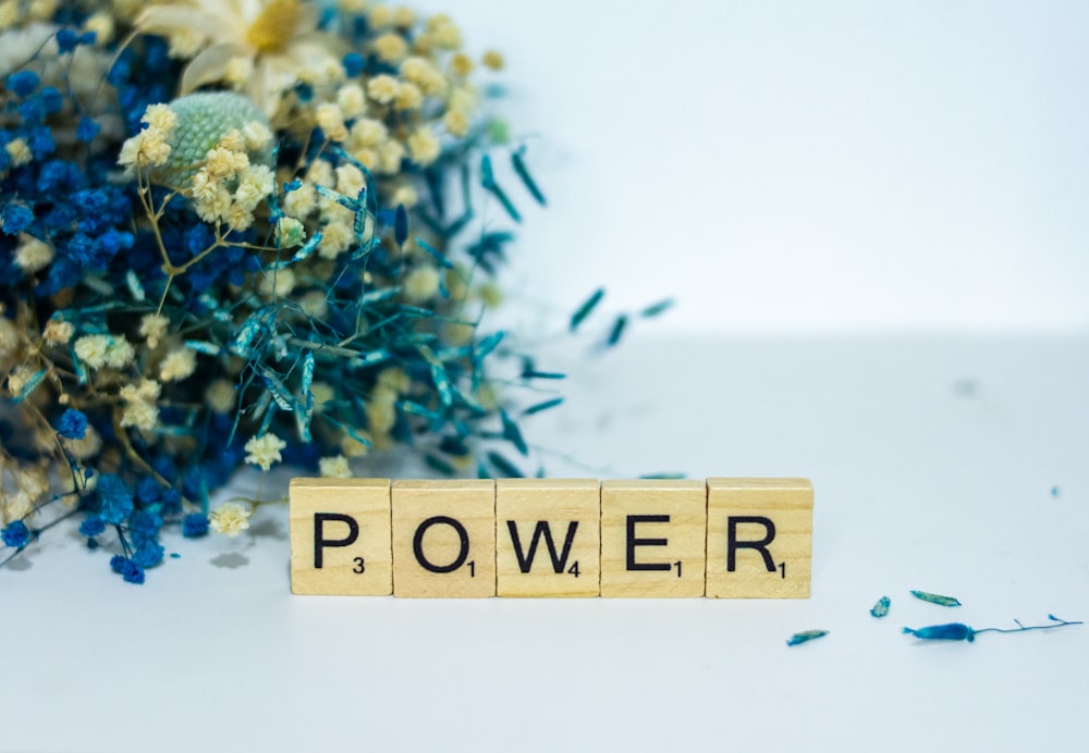 a wooden block that says power next to a bouquet of flowers