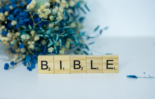 a wooden block spelling the word bible next to a bouquet of flowers