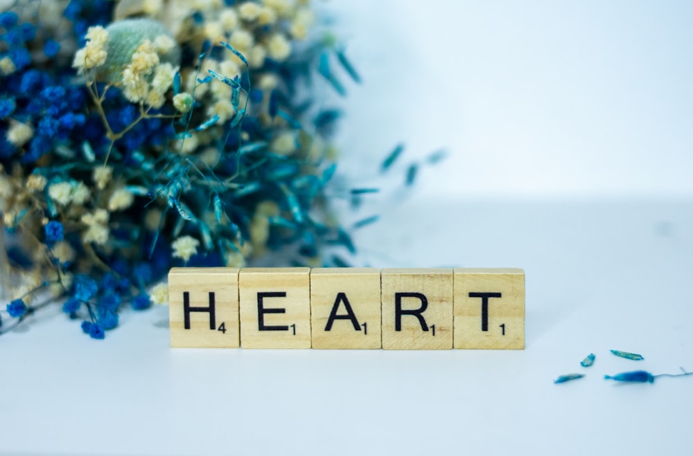 a wooden block spelling the word heart next to a bouquet of flowers