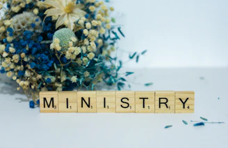 a scrabble block spelling the word mn, in front of a bouquet of