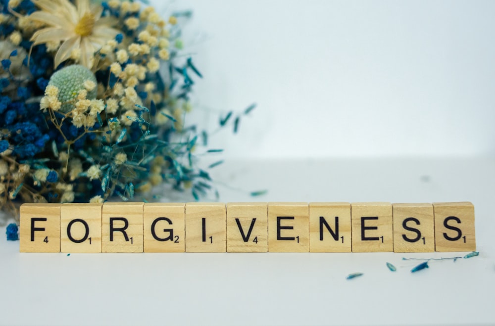 Ein Scrabble-Block, der das Wort Vergebung buchstabiert
