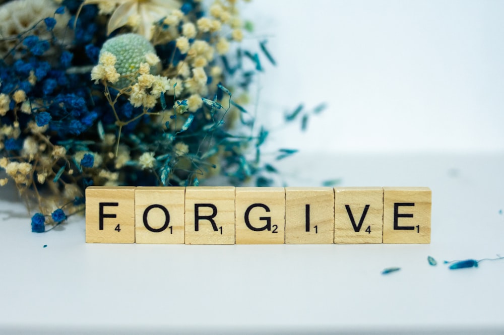 a wooden block that says for give next to a bouquet of flowers