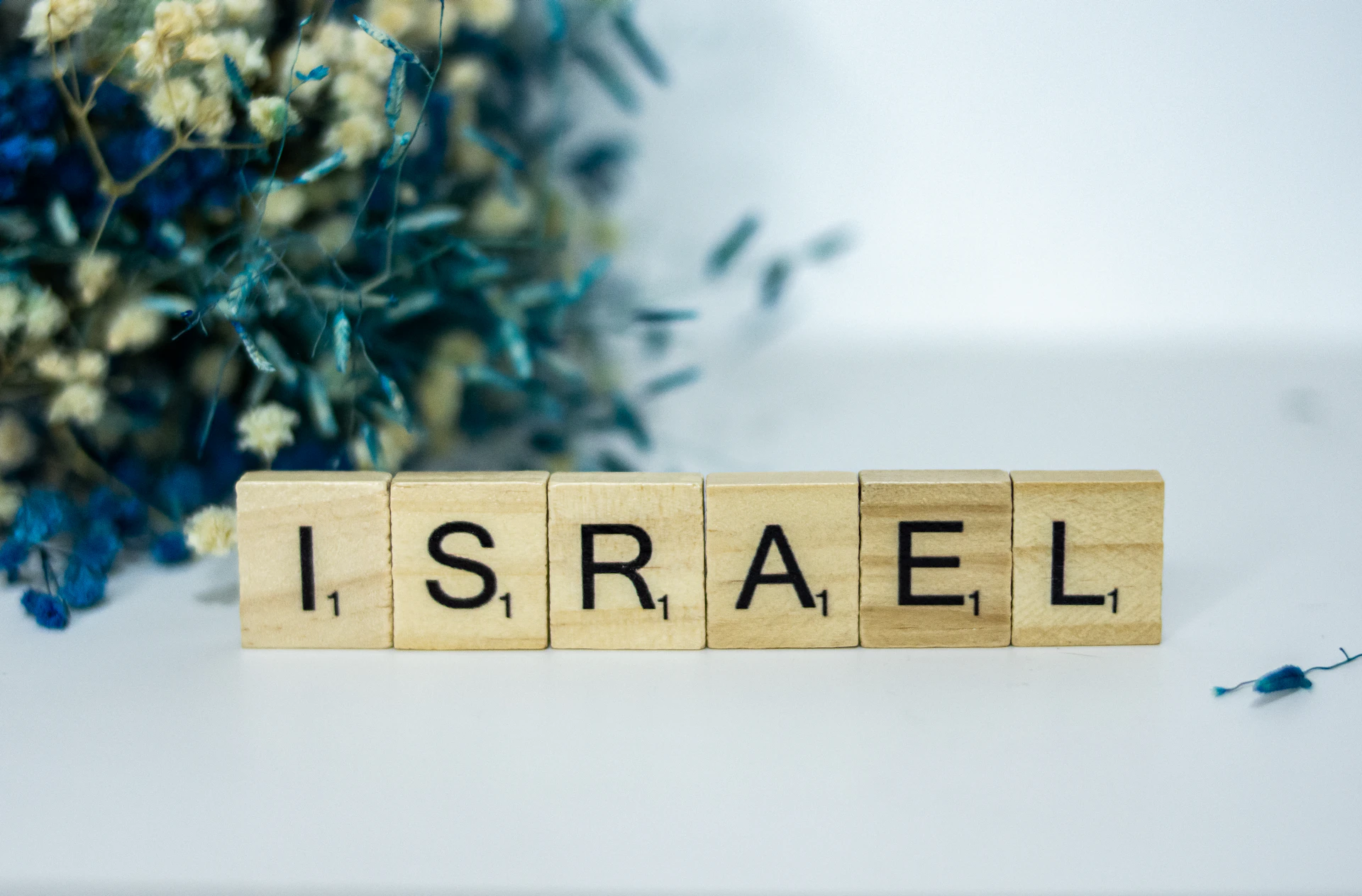 a wooden block spelling israel next to a bouquet of flowers