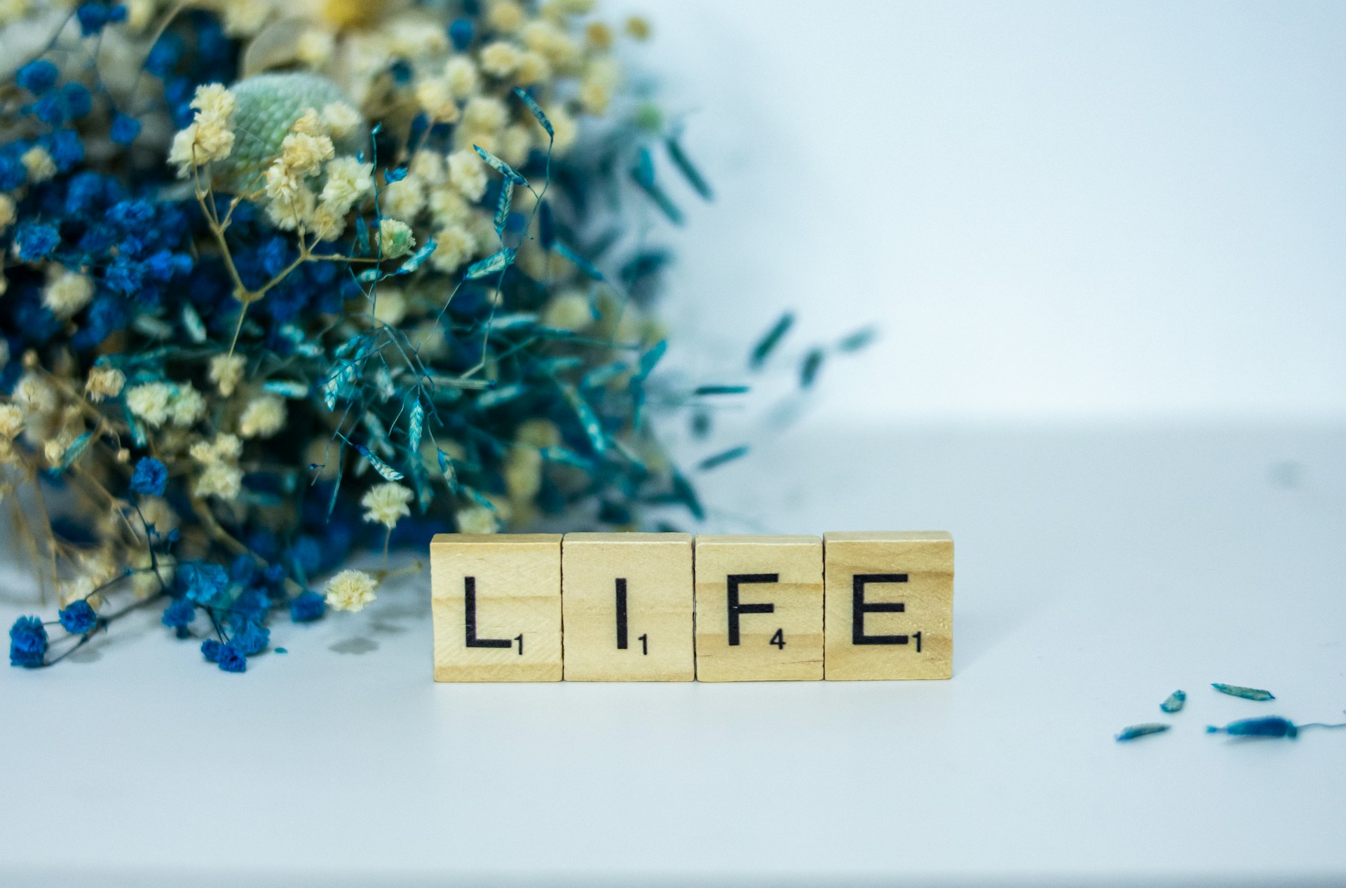 a wooden block that says life next to a bouquet of flowers