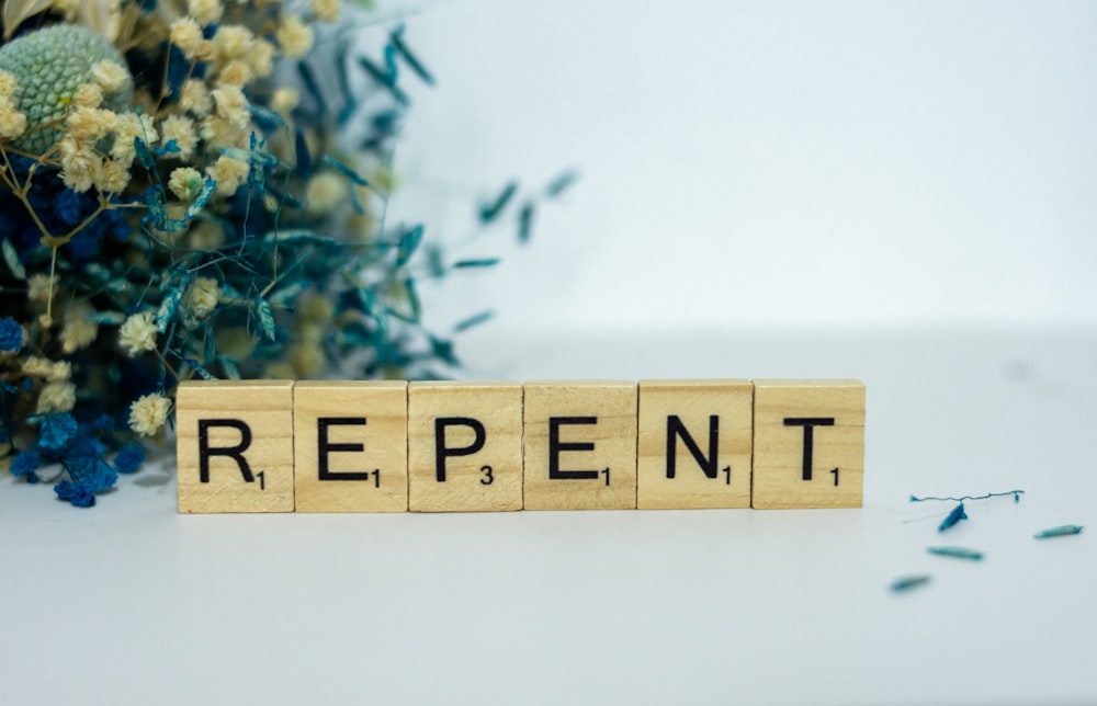 a wooden block that says repent next to a bouquet of flowers