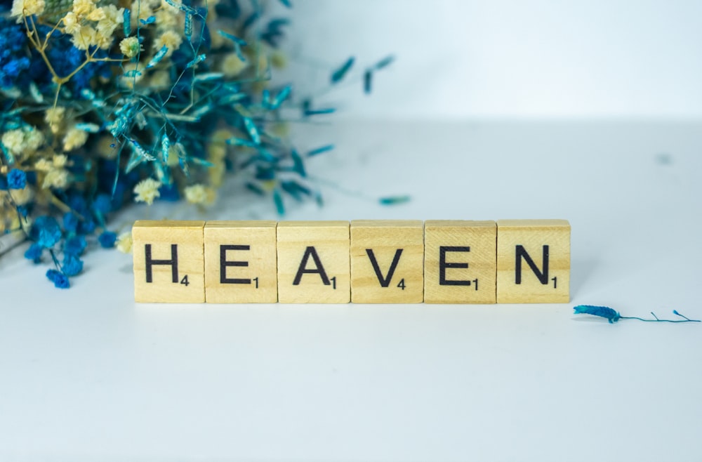 a wooden block that says heaven next to a bouquet of flowers