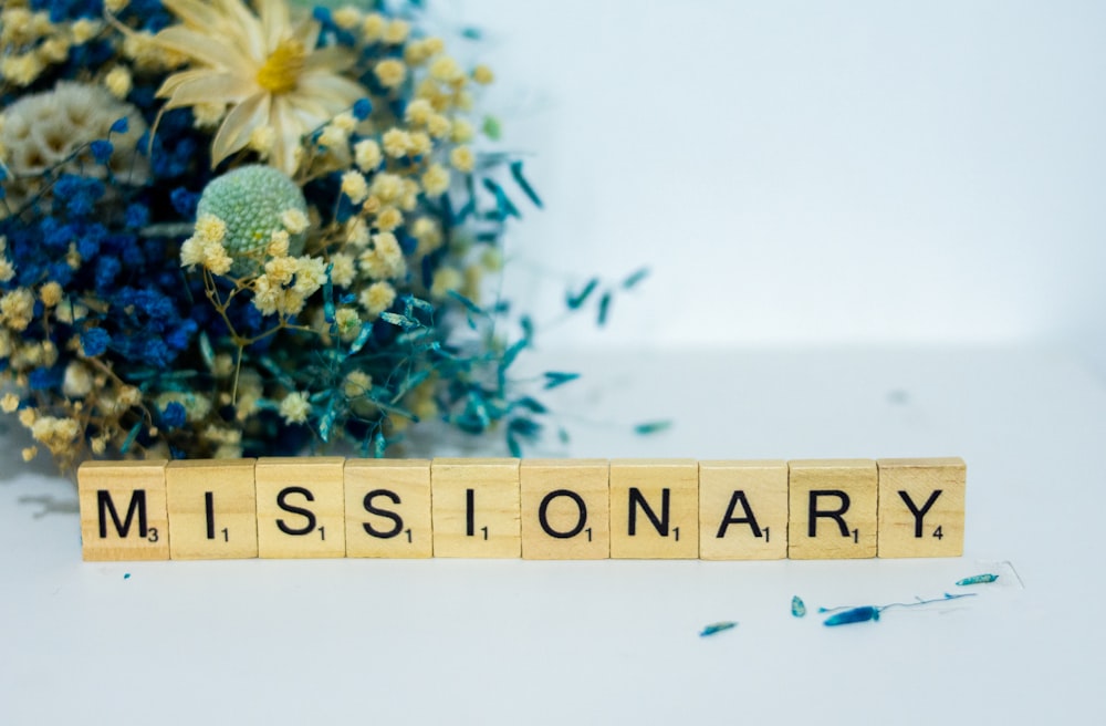 a wooden block that says,'missionary'next to a bouquet of flowers