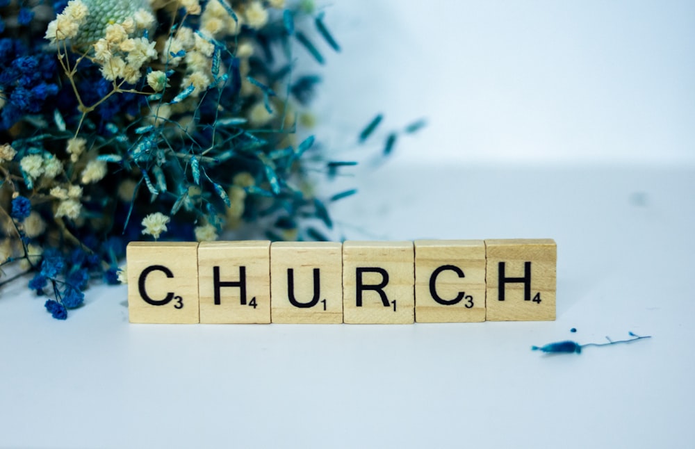 a wooden block that says church next to a bouquet of flowers