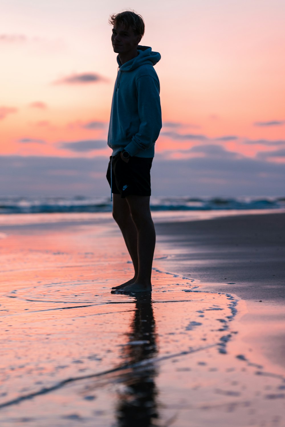 Un homme debout au sommet d’une plage au bord de l’océan