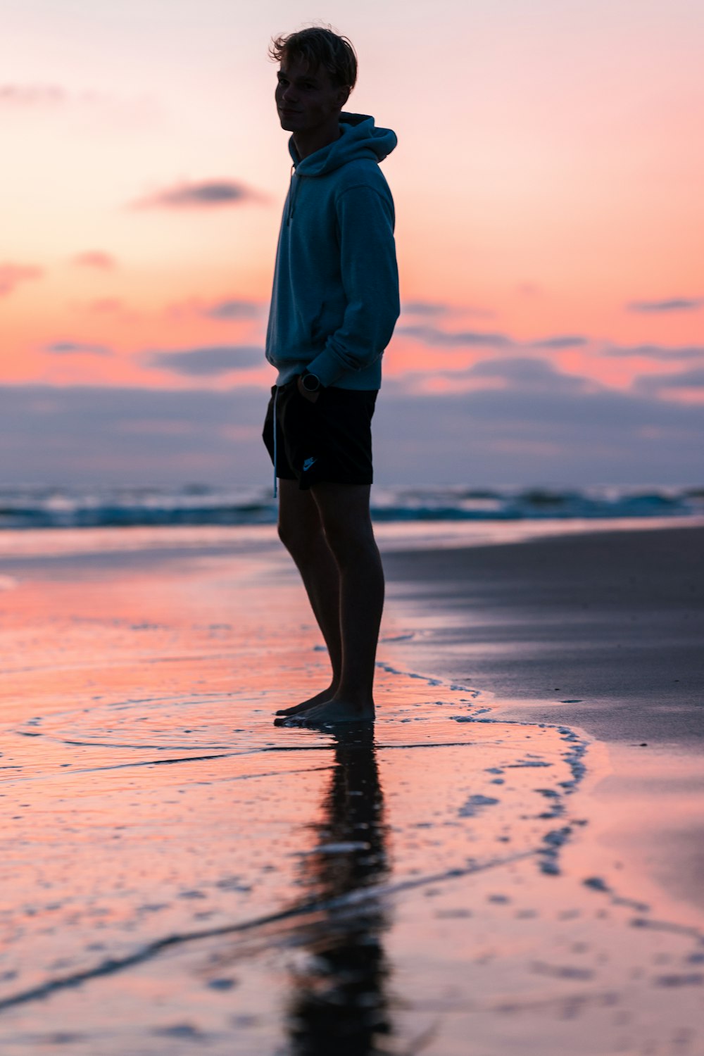 a man standing on top of a beach next to the ocean