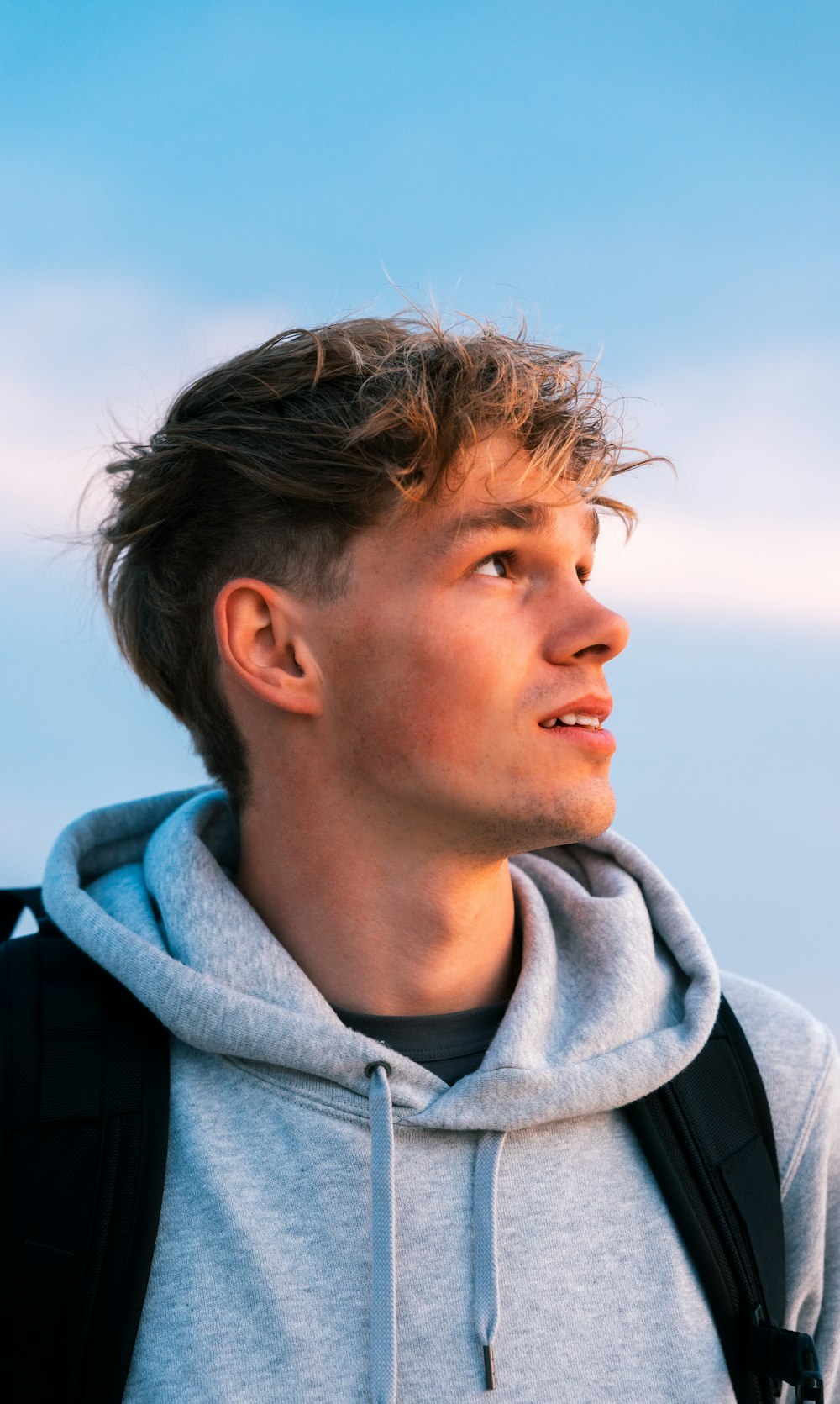 a young man with a backpack looking off into the distance