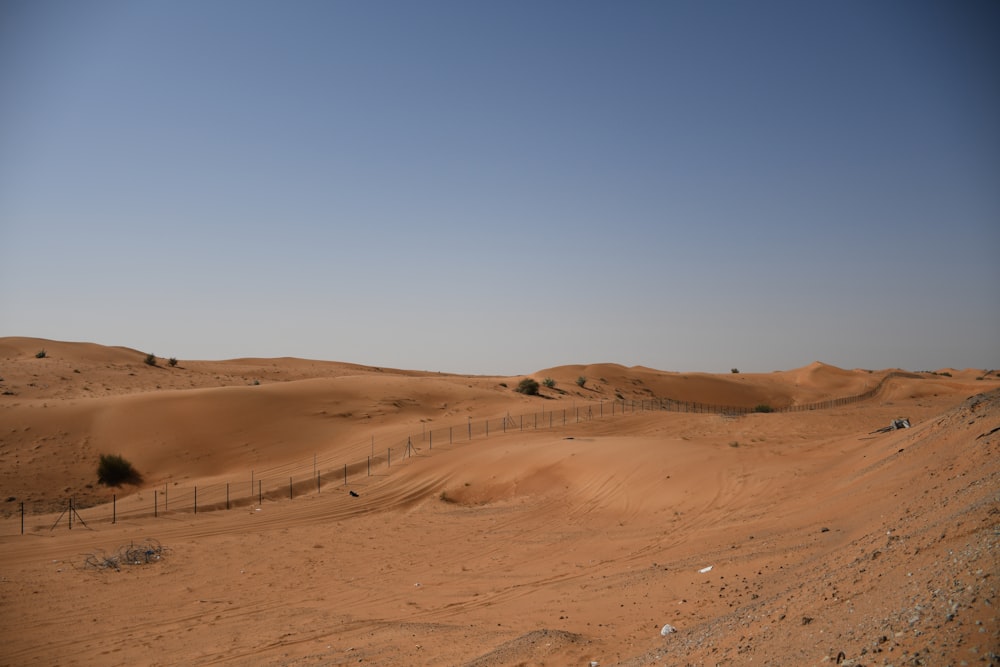 a dirt field with a fence in the middle of it