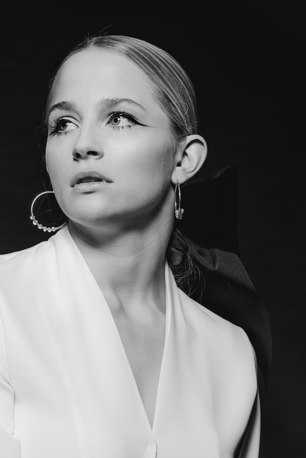 a black and white photo of a woman wearing earrings