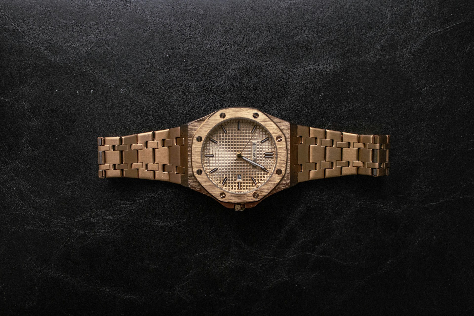 a wooden watch sitting on top of a black surface