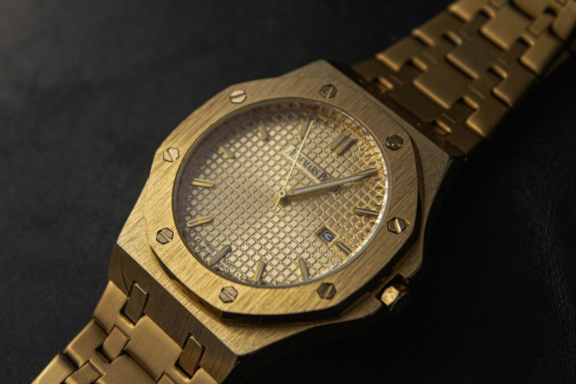 a gold watch sitting on a black surface