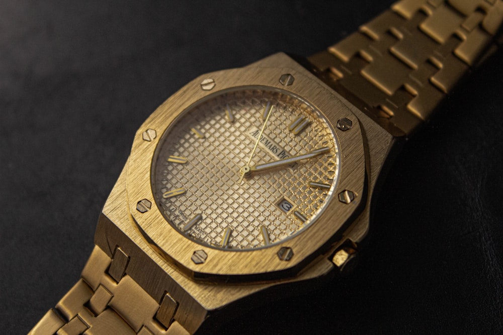 a gold watch sitting on a black surface