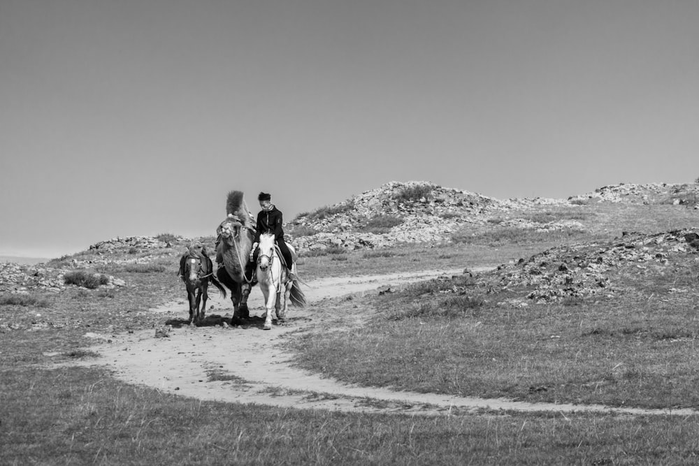 a couple of people riding on the backs of horses