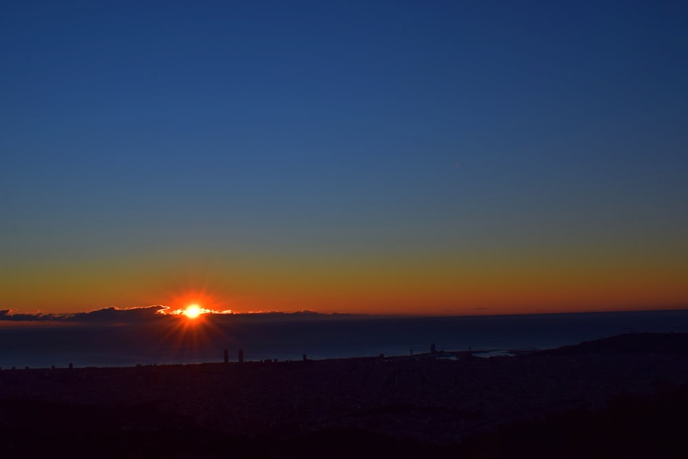 the sun is setting over the horizon of a large body of water