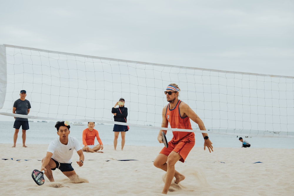 um grupo de homens jogando uma partida de vôlei na praia