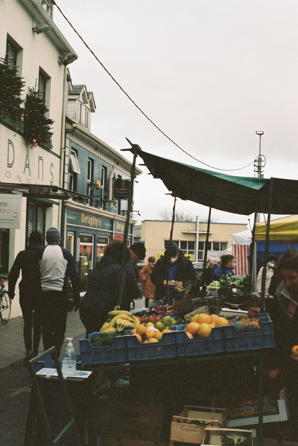 a group of people standing around a table filled with fruit