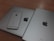 A silver iPhone is placed on top of two larger silver devices, likely a MacBook and an iPad, all featuring the Apple logo.