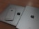 A silver iPhone is placed on top of two larger silver devices, likely a MacBook and an iPad, all featuring the Apple logo.