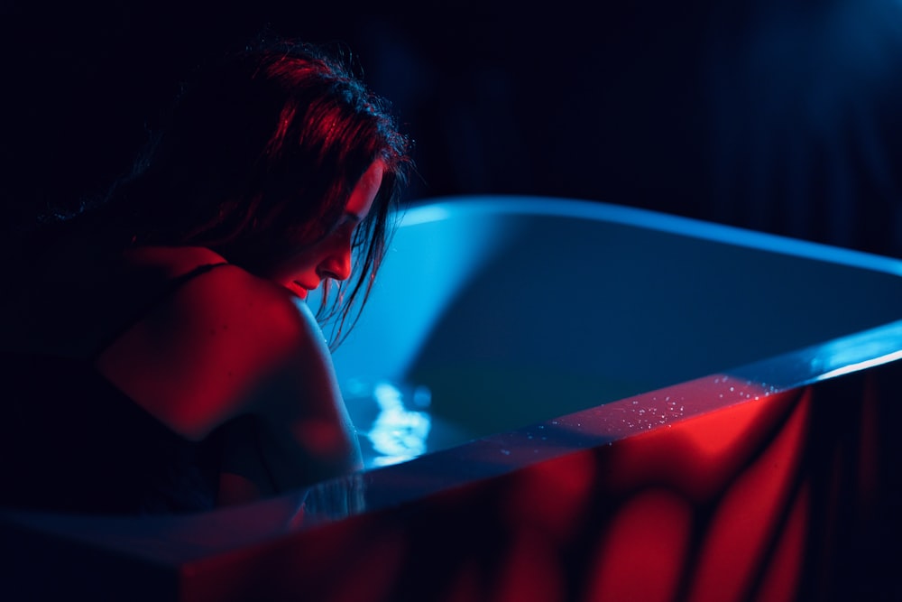 a woman sitting in a bathtub in the dark